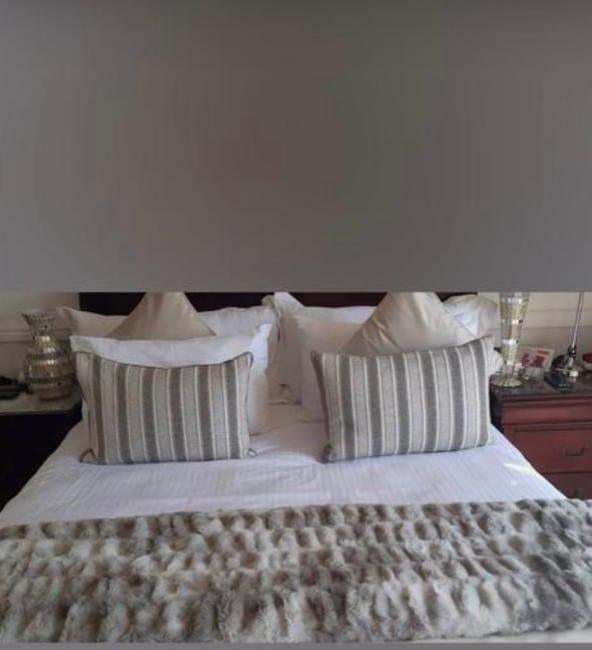 Bed dressed with striped bolster cushions and a faux-fur runner