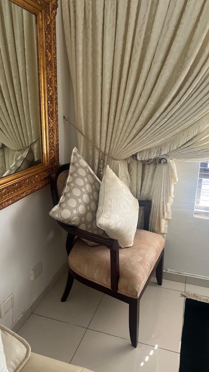Scatter cushions on an accent chair beside a curtain corner