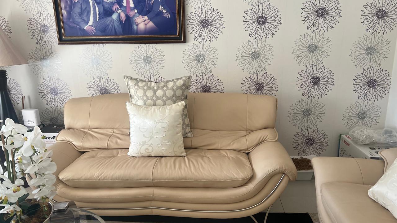Two tailored scatter cushions on a cream leather sofa against floral wallpaper